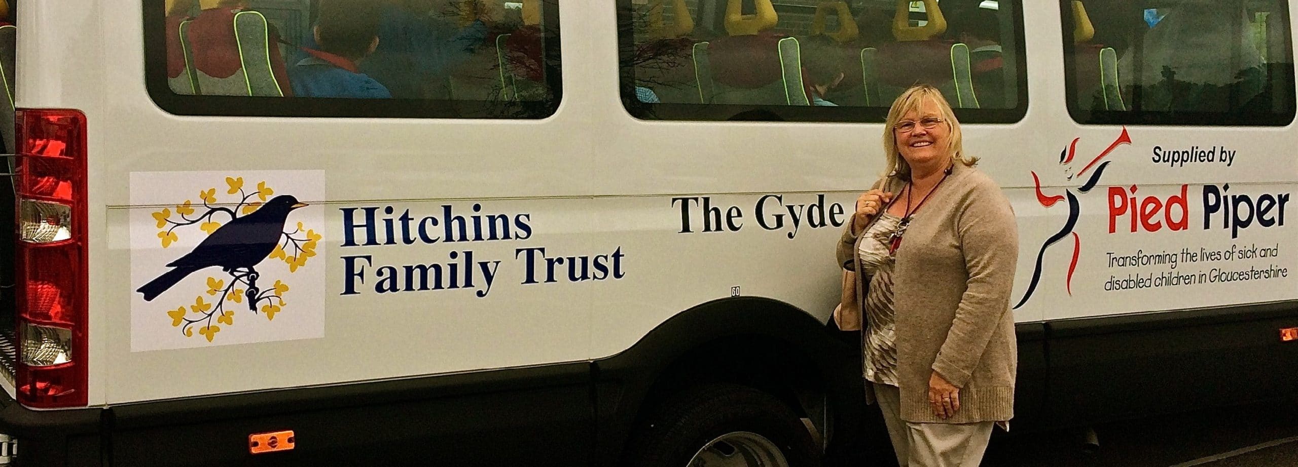 A woman is standing in front of a mini bus
