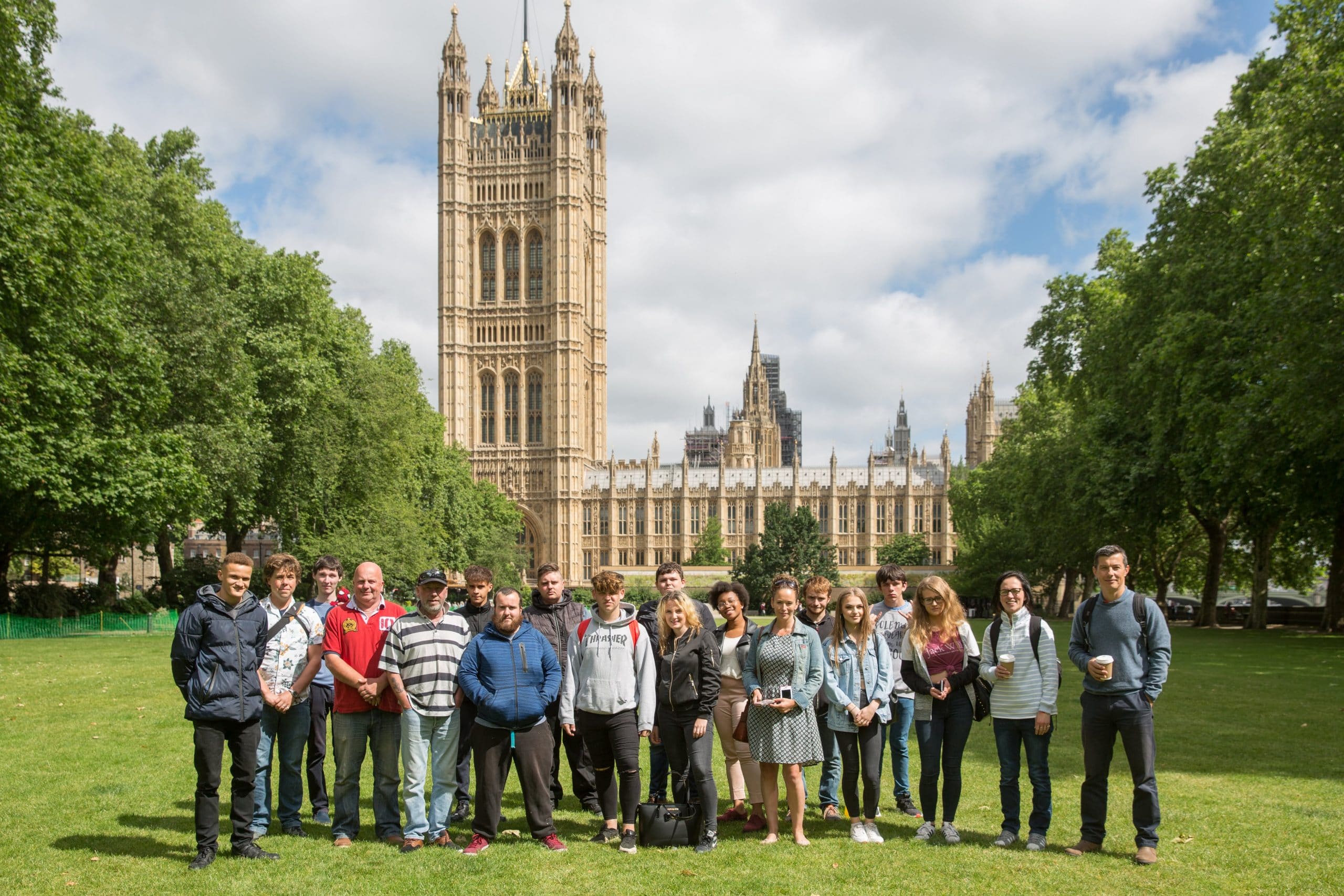 A group of young people stands in front of the Houses of Parliament building