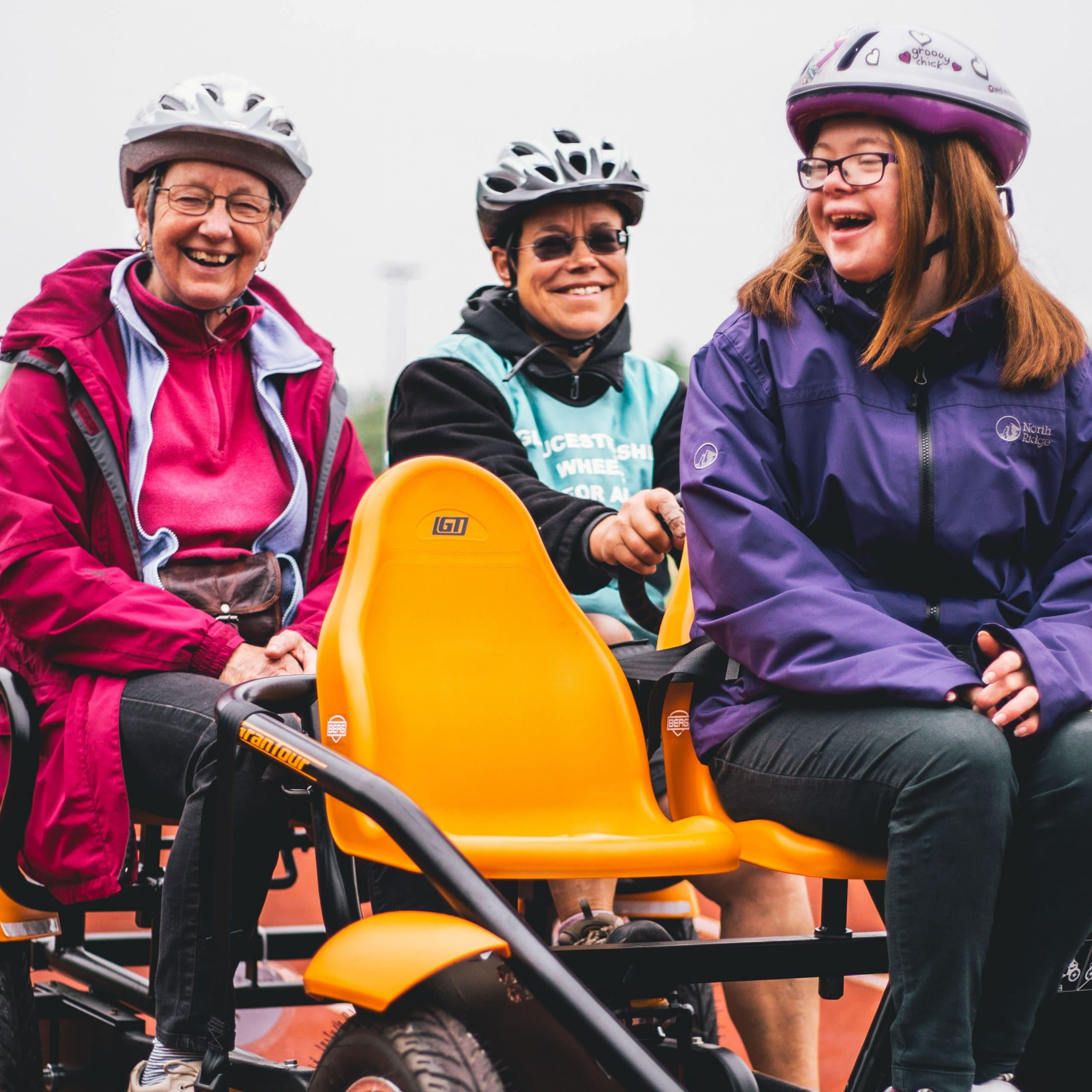 People riding on an adapted disabilitybicycle smiling and laughing