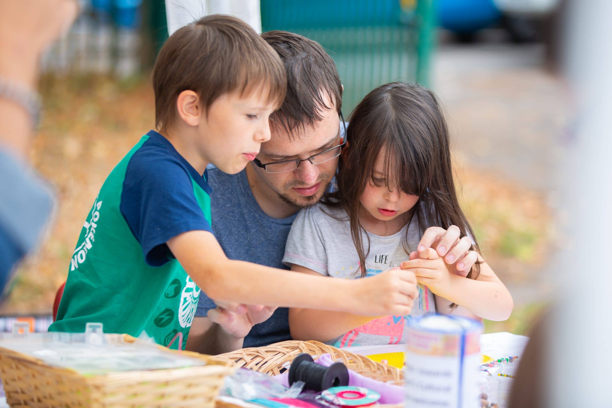 An adult and two children work together on a handmade craft