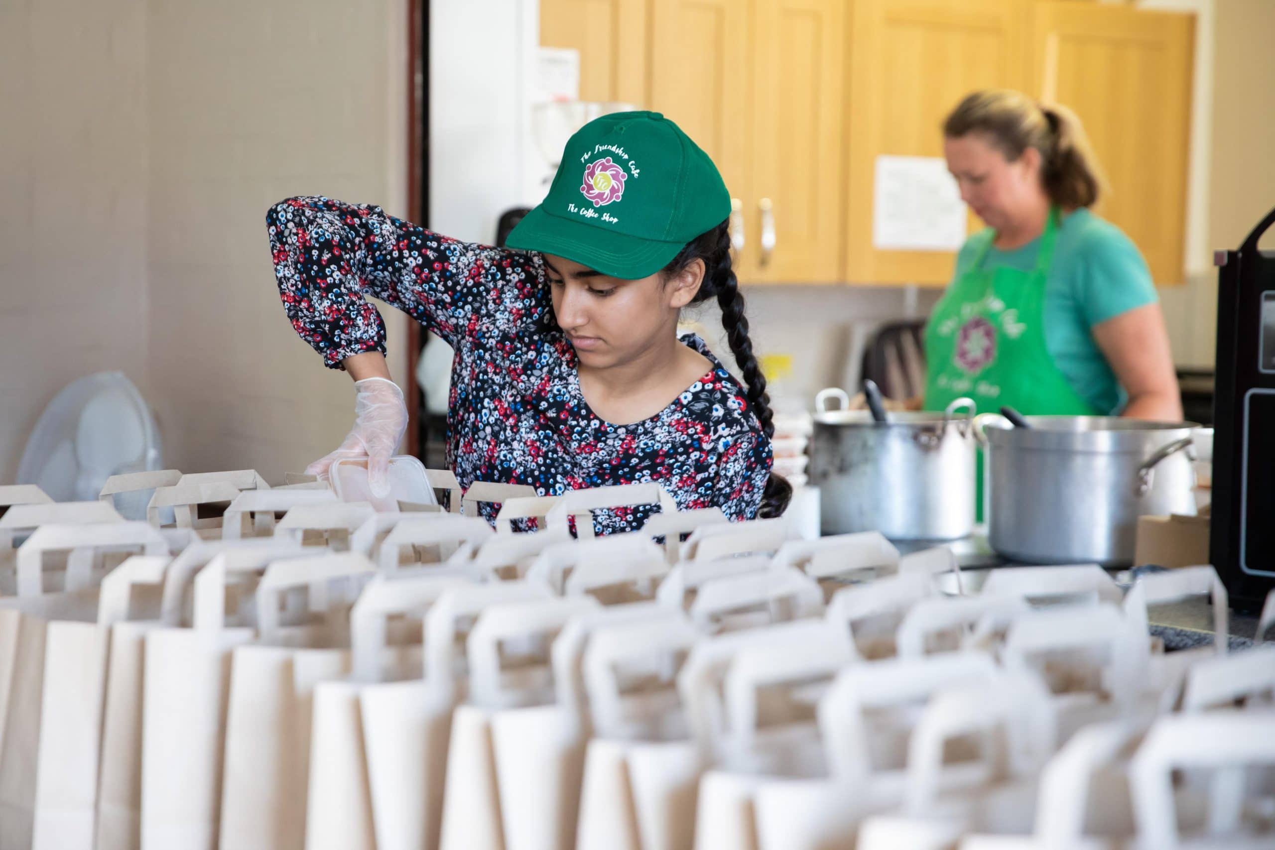 A picture of a girl in a green cap putting food in paper bags
