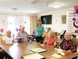 People sat around a table with a Cotswold Friends banner in the background