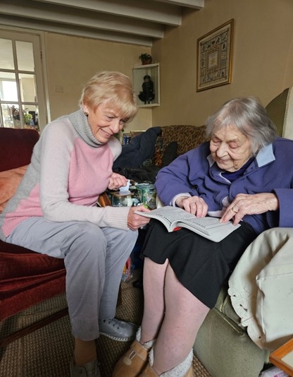 Two women sit together reading a book