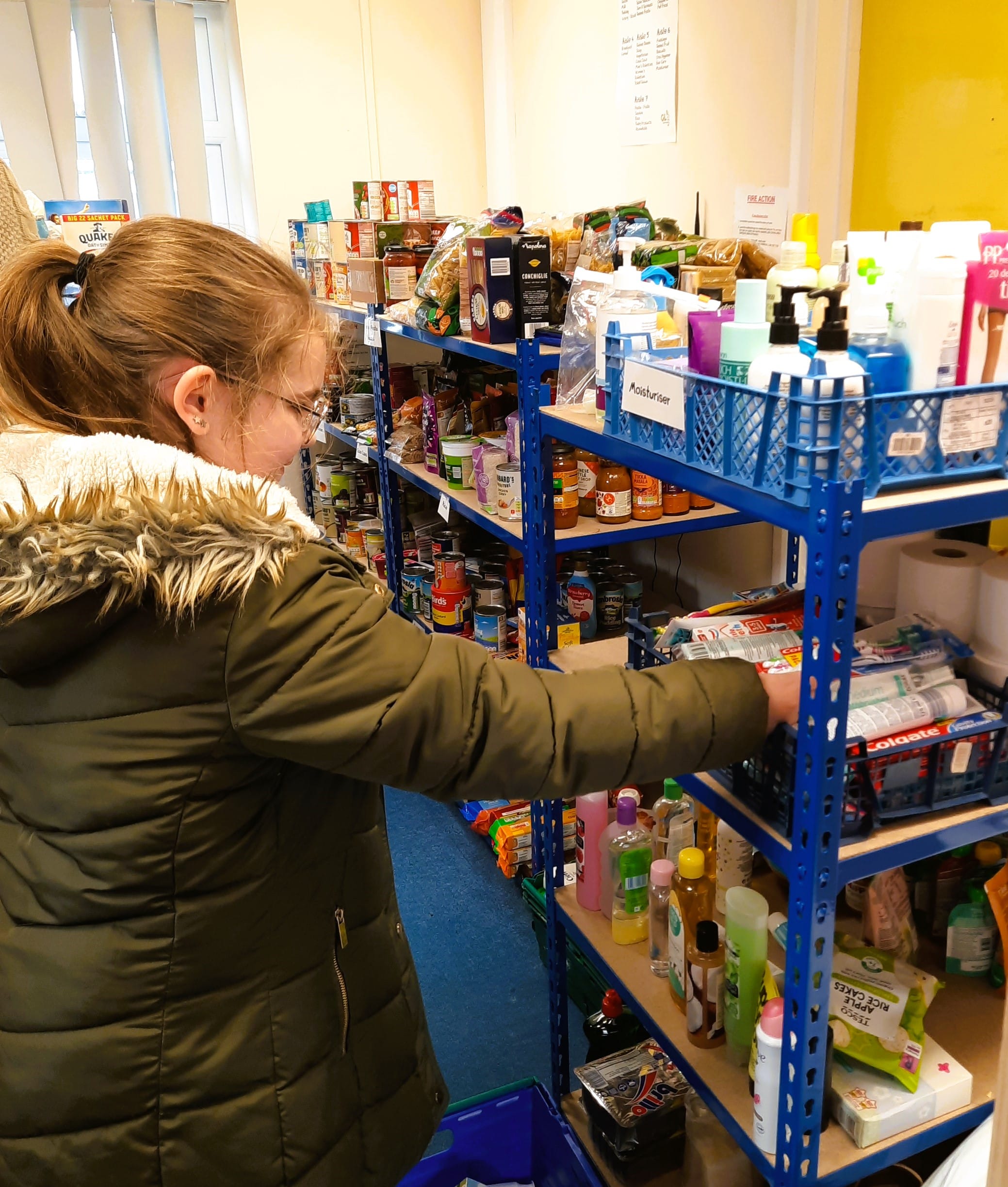 Young girl chooses items from GL11 Food Pantry shelves